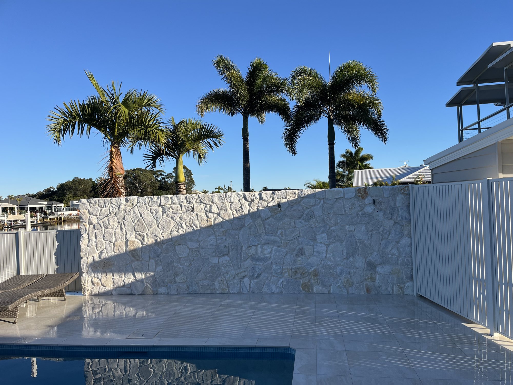 Natural stone pool feature wall with palms - Stone Cladding Sunshine Coast