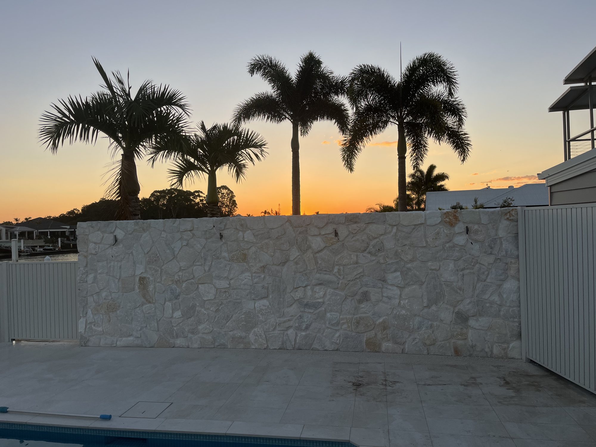 Natural stone feature wall by the pool at sunset – Stone Cladding Sunshine Coast Natural stone feature wall by the pool at sunset - Stone Cladding Sunshine Coast