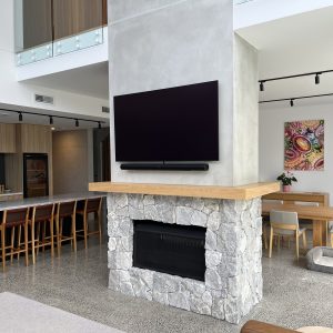 Natural stone clad fireplace with TV wall in open plan living - Stone Cladding Sunshine Coast