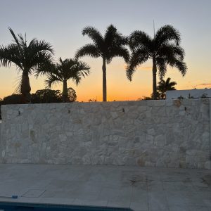 Natural stone feature wall by the pool at sunset - Stone Cladding Sunshine Coast