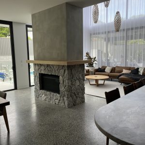 Natural stone clad double-sided fireplace in open plan living - Stone Cladding Sunshine Coast
